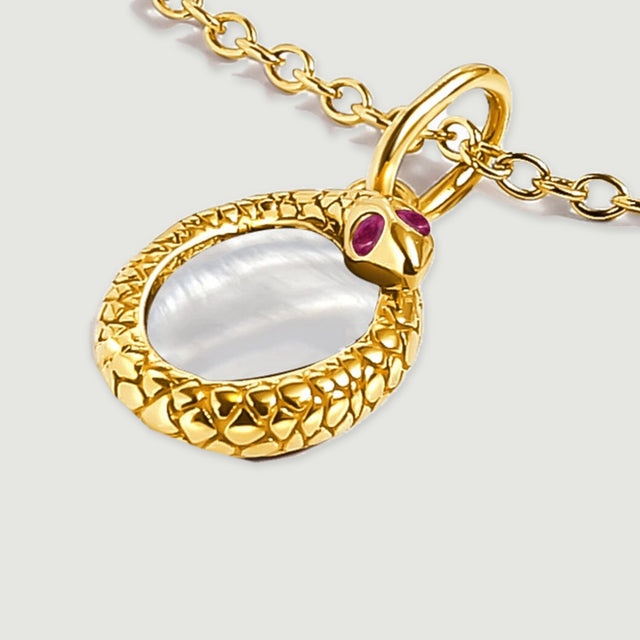 The yellow gold plated pendant rests at an angle with its curved bail and sculpted rim visible.