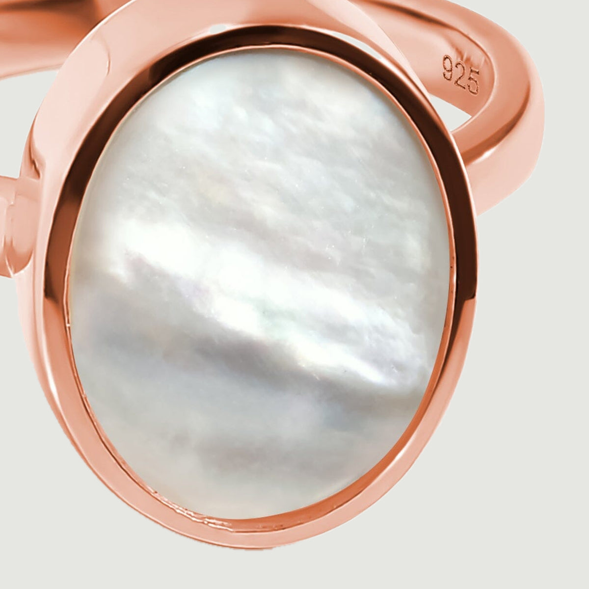 A close view shows pearly white layers inside the oval rose gold bezel.