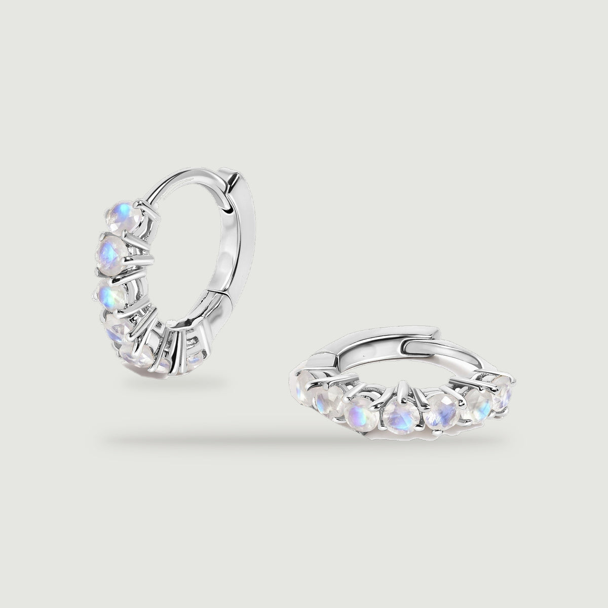 A pair of silver-tone moonstone hoops rests against a light gray background.