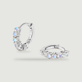 A pair of silver-tone moonstone hoops rests against a light gray background.