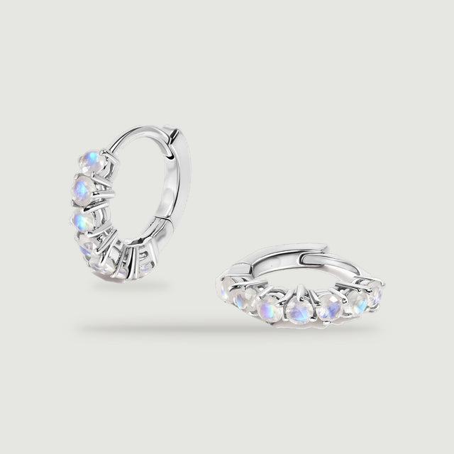 A pair of silver-tone moonstone hoops rests against a light gray background.