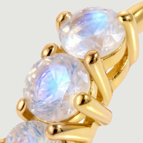 Round moonstones sit in polished yellow-gold-tone prongs in a tightly framed close-up.