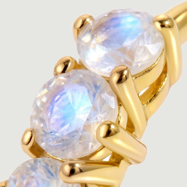 Round moonstones sit in polished yellow-gold-tone prongs in a tightly framed close-up.