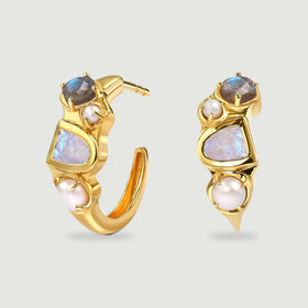 Yellow-gold-tone hoop earrings stand side by side, showing pale central stones, smaller round stones and white pearls.