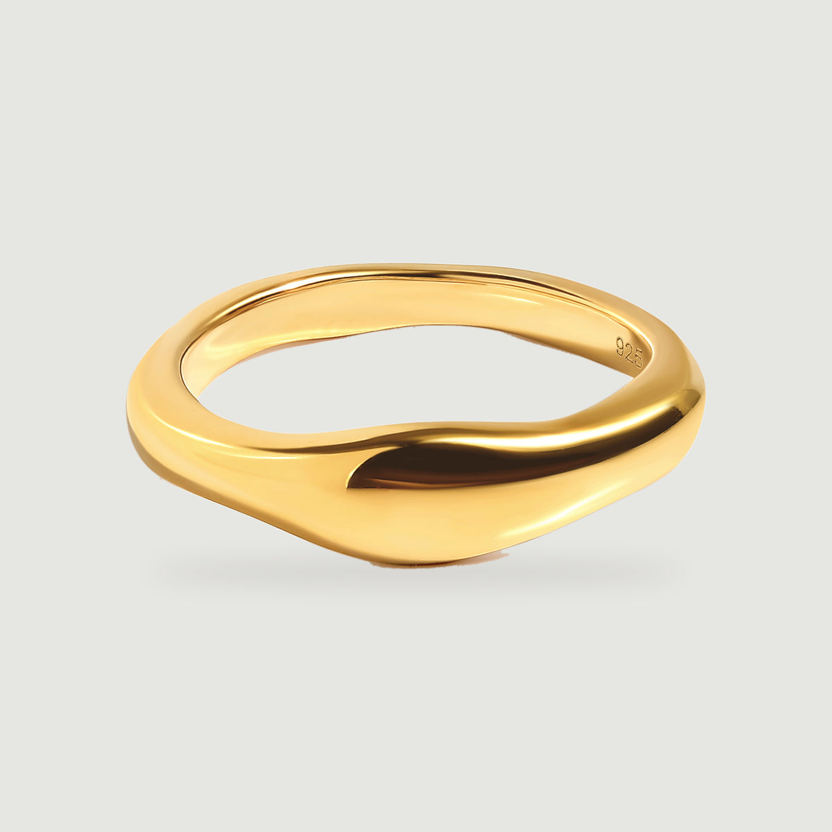A polished yellow gold vermeil ring with a gently widened curved face rests on a pale grey background.
