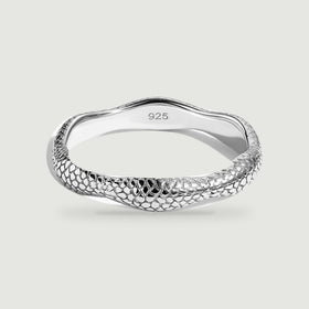 A silver ring with a rippled edge and raised textured surface rests on a pale gray background.
