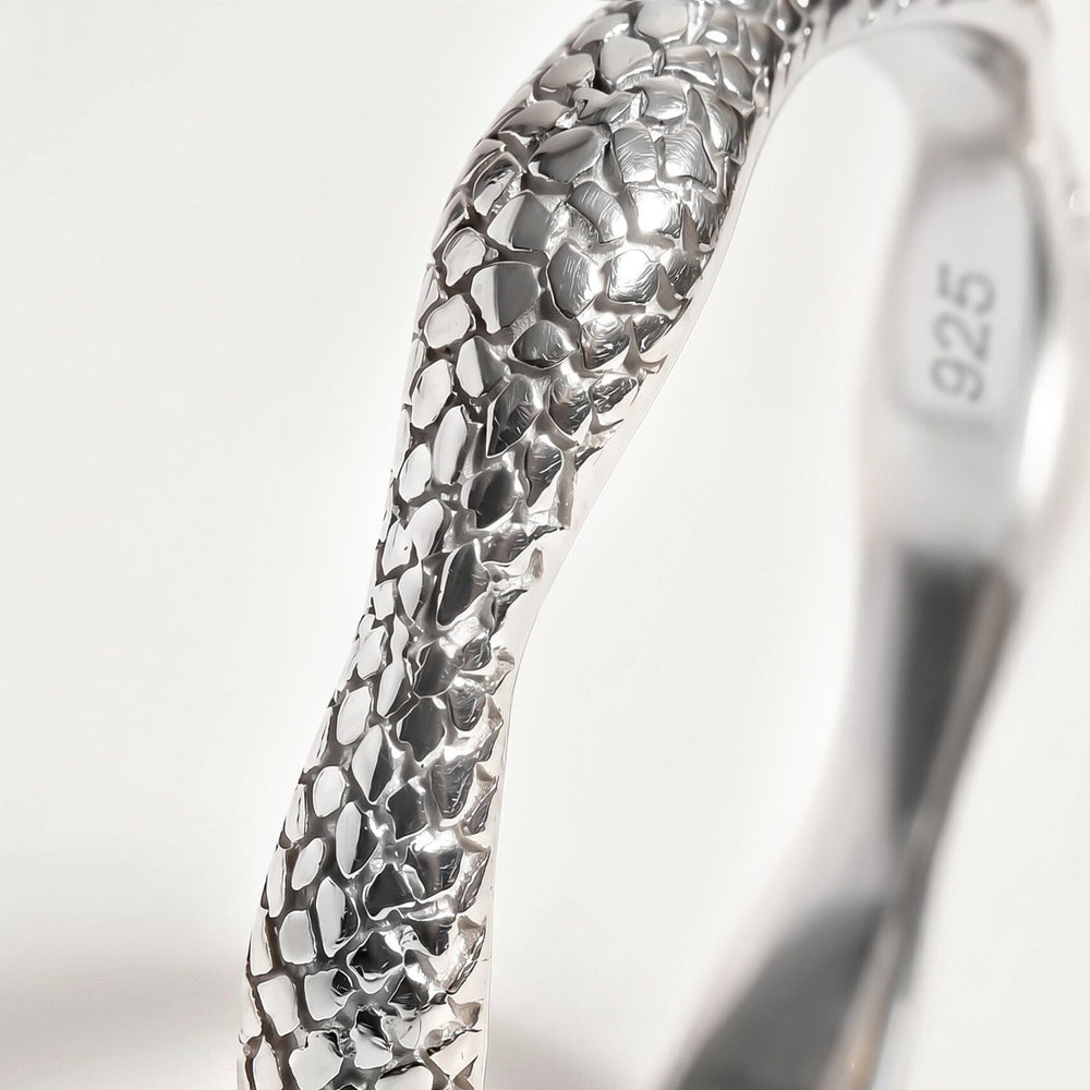 A close view of the silver band shows irregular polished shapes and dark recessed lines.