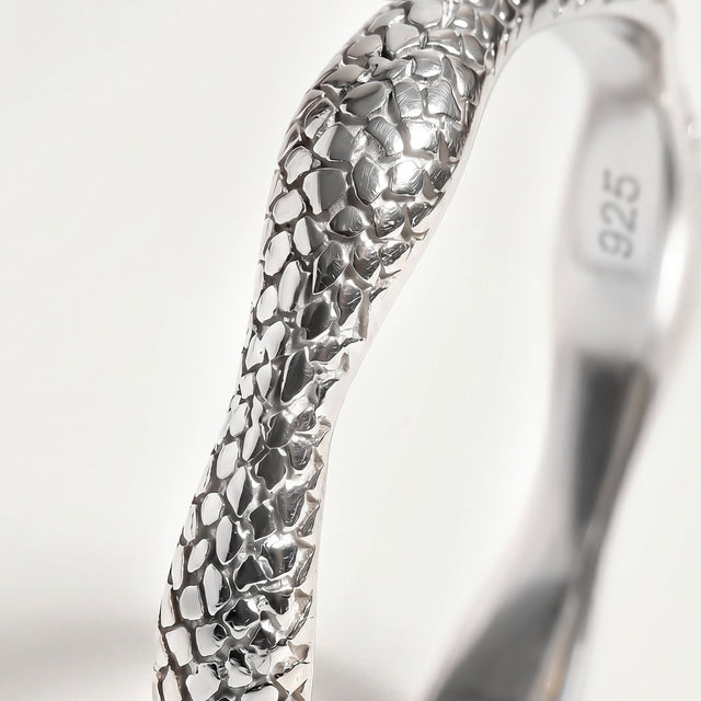 A close view of the silver band shows irregular polished shapes and dark recessed lines.