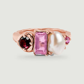 A rose gold ring shows its smooth band behind a red round gemstone, a pink rectangular gemstone, and a softly curved white pearl.