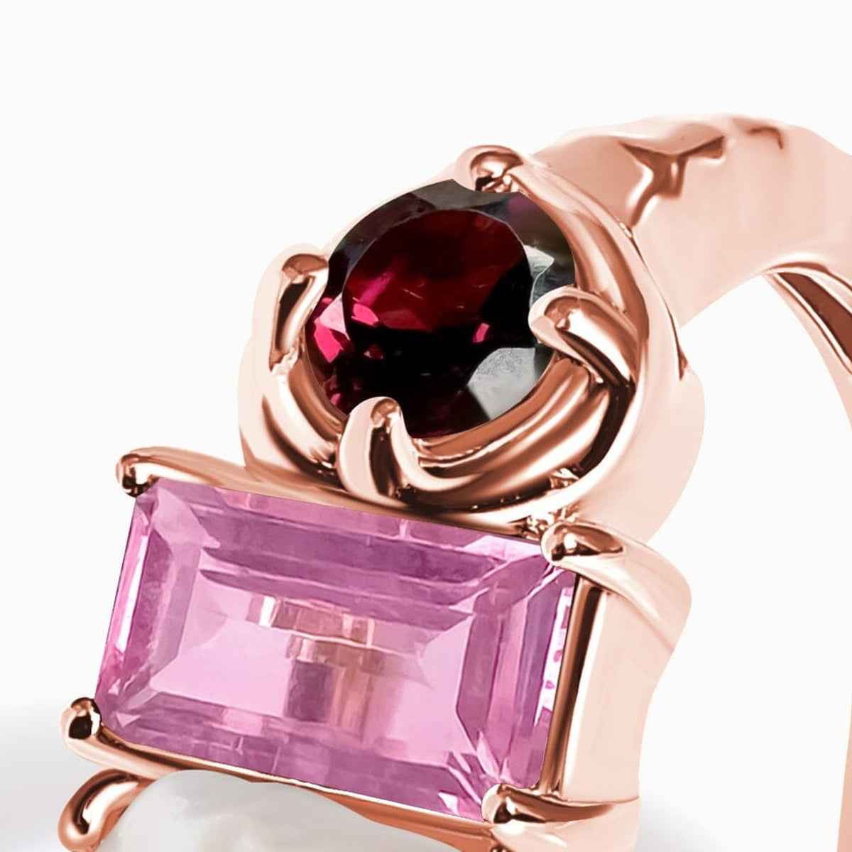 A close angled view shows a red faceted round gemstone above a pink rectangular stone in rose gold prongs.