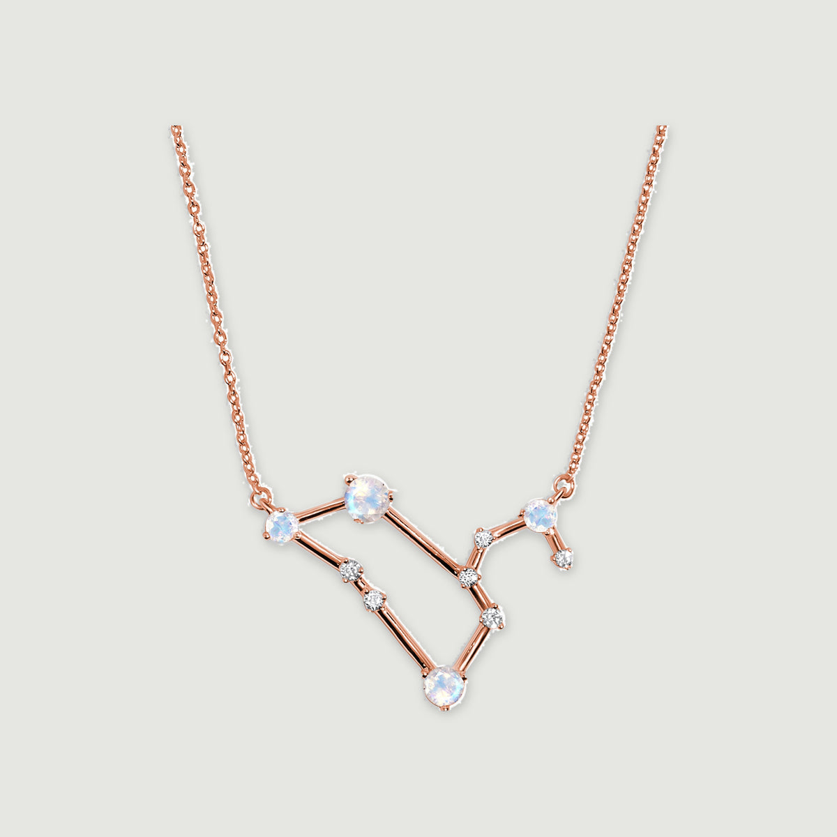 A rose gold chain joins a geometric moonstone pendant displayed centrally against a light gray surface.
