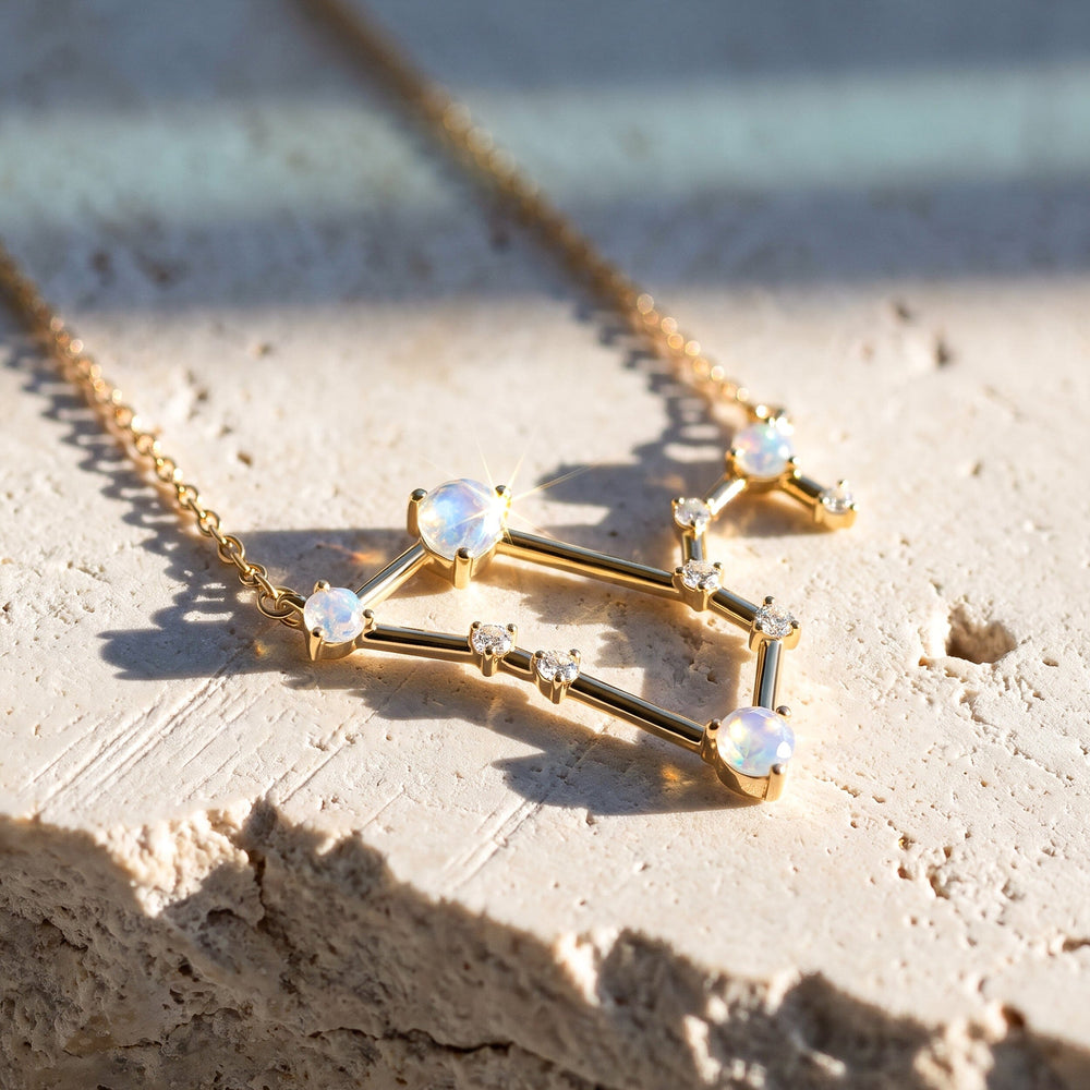 The yellow gold pendant rests on textured pale stone with its round moonstones catching the sunlight.