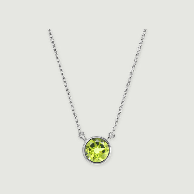 A white gold chain meets a circular bezel holding a faceted green peridot against a pale gray background.