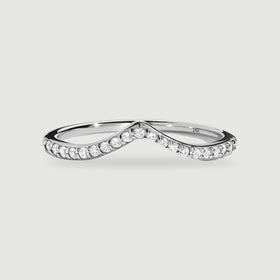 A white gold ring with a pointed diamond-set band rests on a light gray surface.