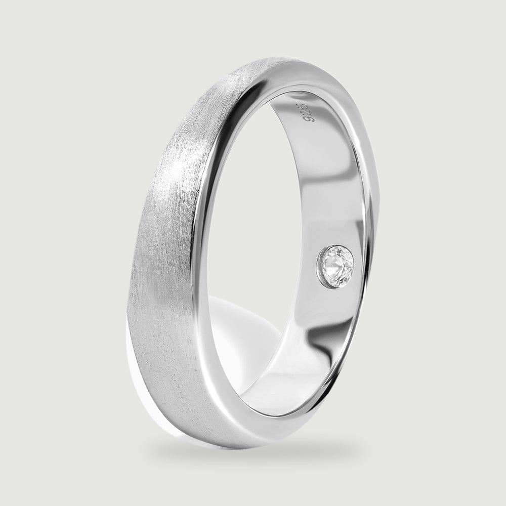 The silver band stands at an angle, showing its rounded profile and polished inner surface.