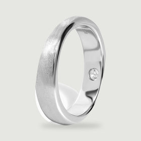 The silver band stands at an angle, showing its rounded profile and polished inner surface.