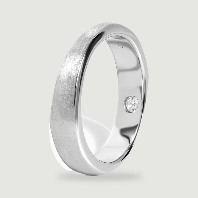 The silver band stands at an angle, showing its rounded profile and polished inner surface.