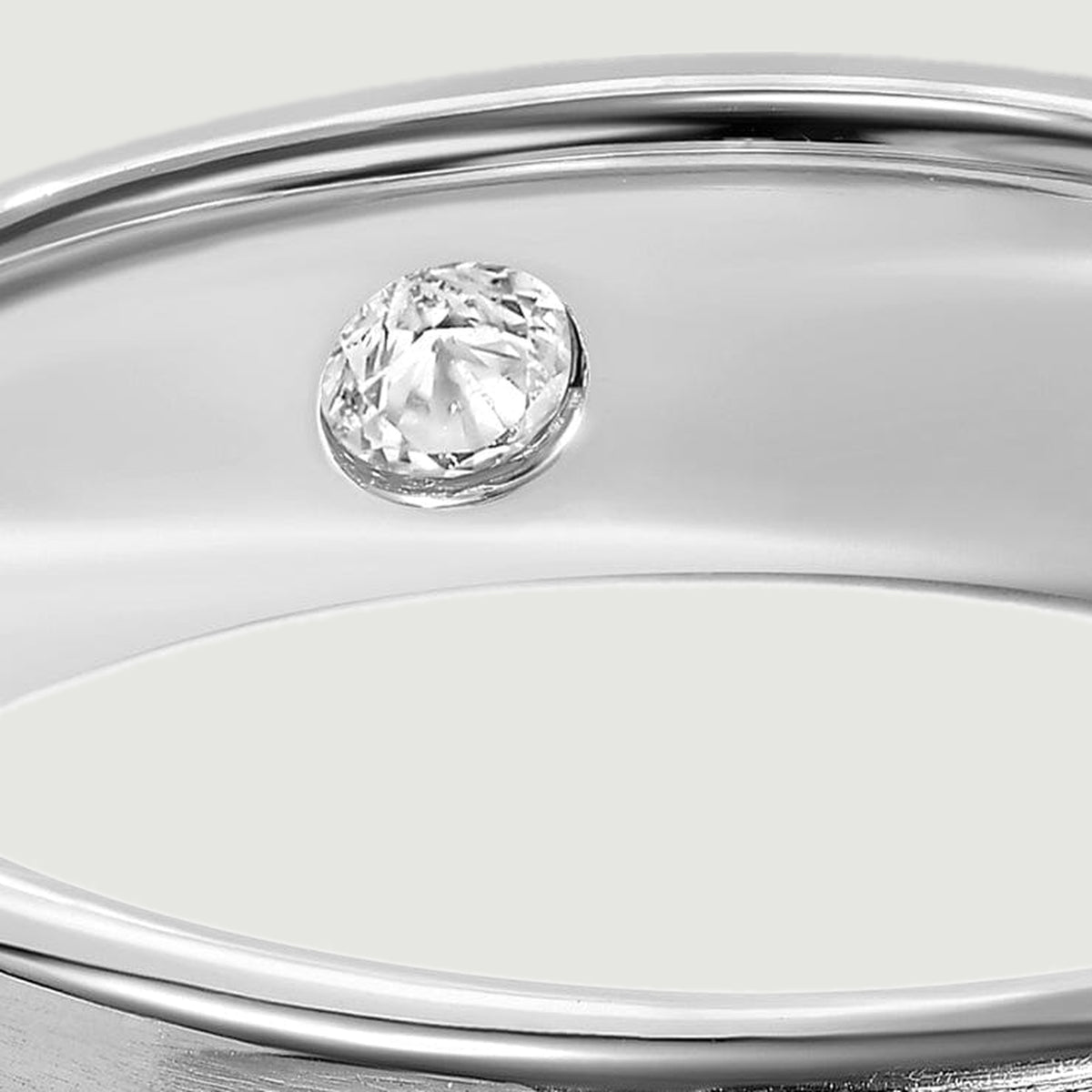 A round clear stone sits inside the reflective silver band beneath the polished upper edge.