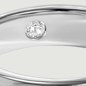 A round clear stone sits inside the reflective silver band beneath the polished upper edge.