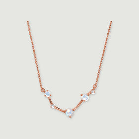 A rose gold necklace displays three round moonstones and two small clear stones joined by polished bars.