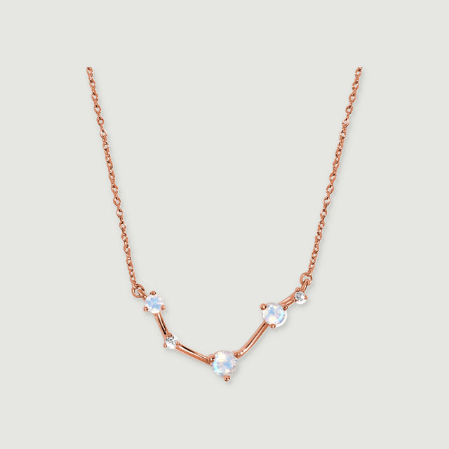 A rose gold necklace displays three round moonstones and two small clear stones joined by polished bars.