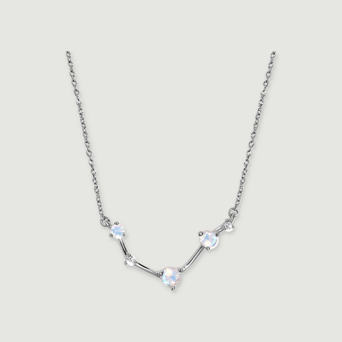 A silver necklace shows blue flashes in three faceted moonstones with small clear accents between them.