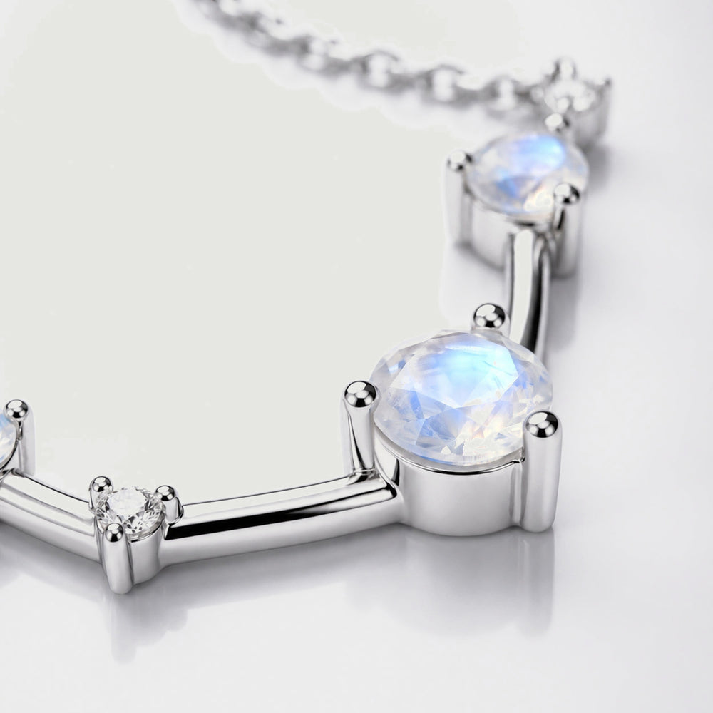 A close view shows a faceted moonstone held by silver prongs beside a small clear stone.