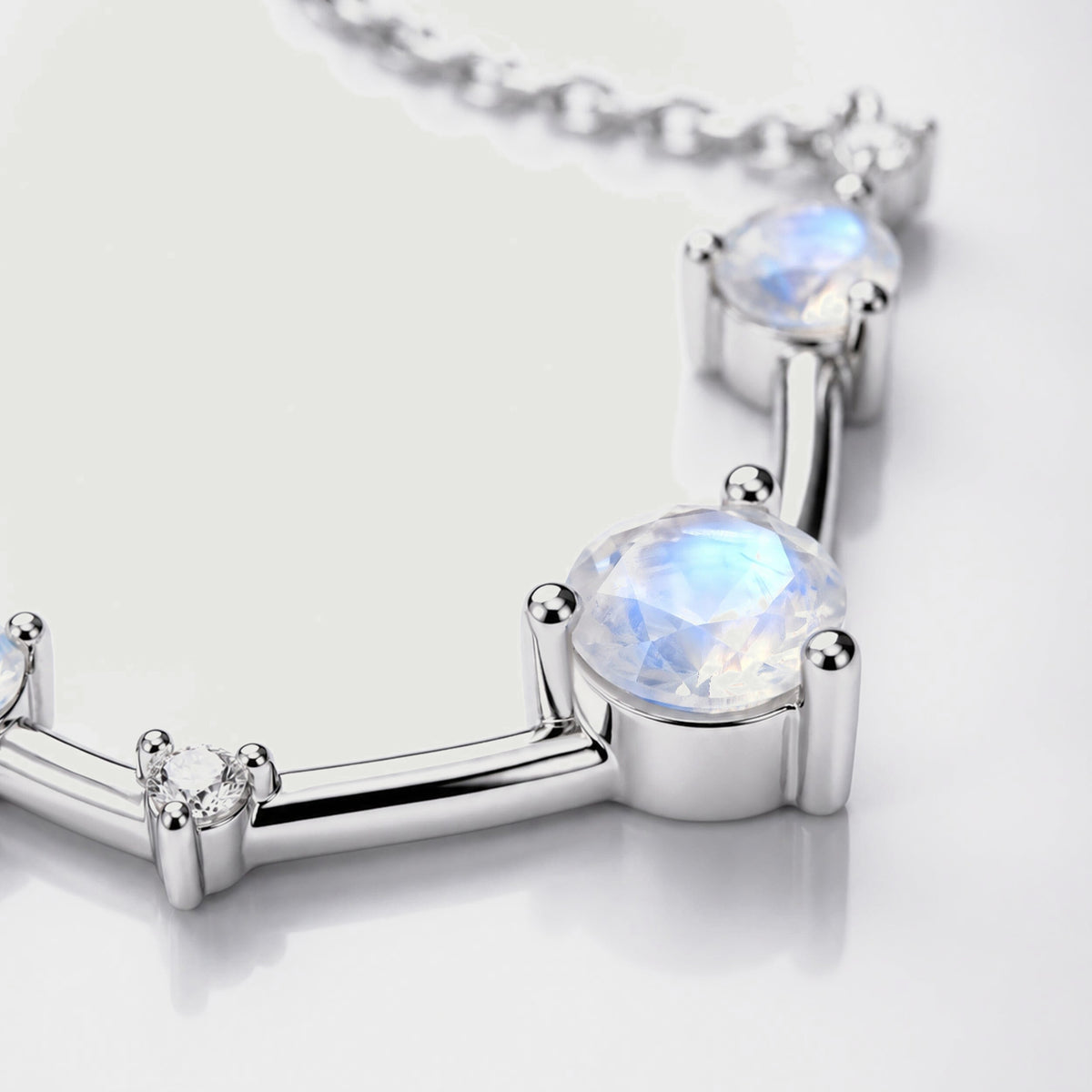 A close view shows a faceted moonstone held by silver prongs beside a small clear stone.