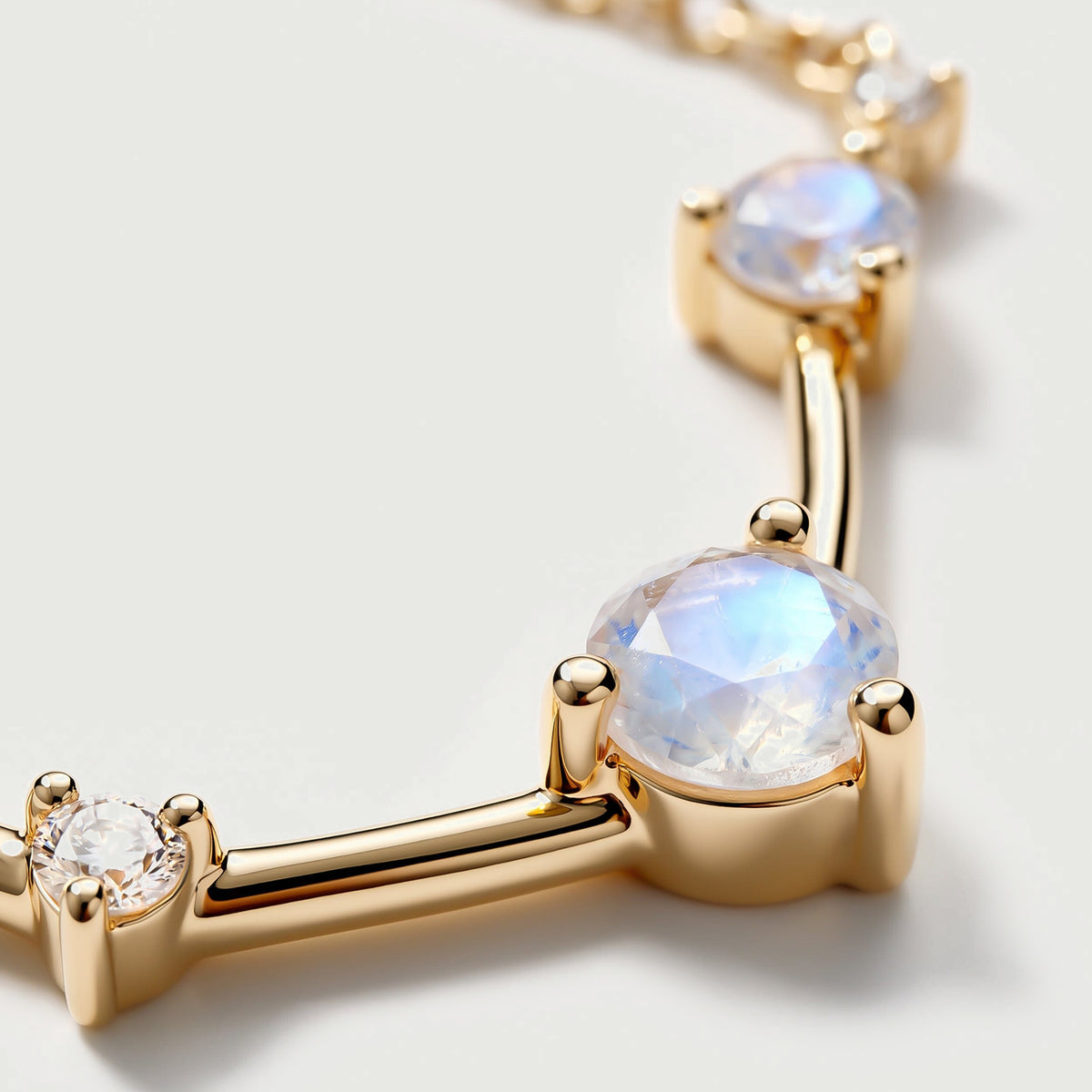 An angled close view reveals a raised yellow gold setting and the polished bar beside a moonstone.