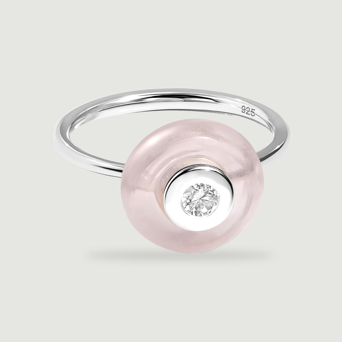 A polished silver band curves behind a pale pink disc with a bright round gem at its center.