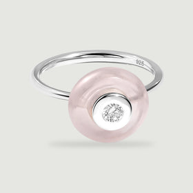 A polished silver band curves behind a pale pink disc with a bright round gem at its center.
