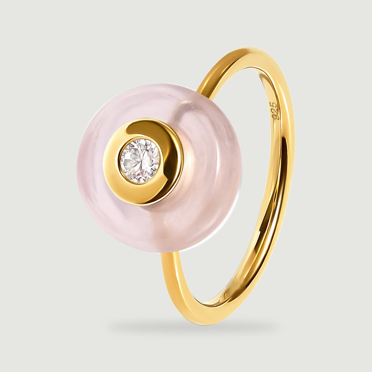An angled yellow gold ring shows its slender band behind the pink stone and clear central gem.