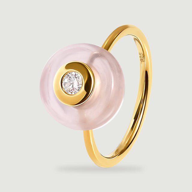 An angled yellow gold ring shows its slender band behind the pink stone and clear central gem.
