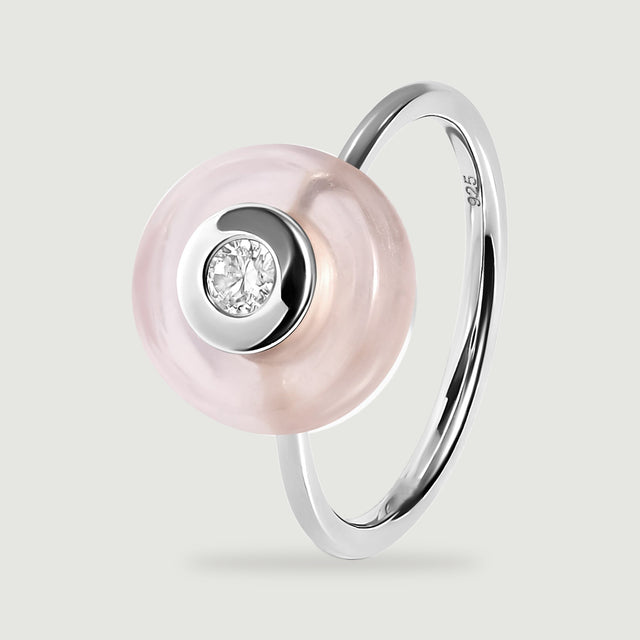 The side angle of a silver ring reveals a slim band and the raised profile of its round pink stone.