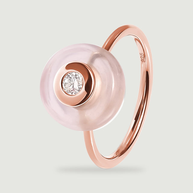 A tilted rose gold ring shows the smooth pink disc in front of its polished curved band.