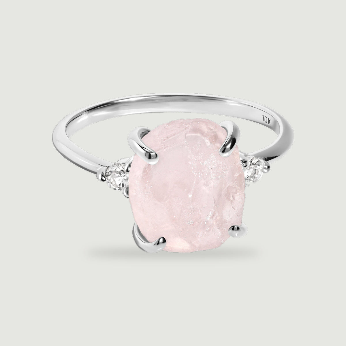 A white gold band curves behind a pale pink rough stone flanked by two small round clear stones.