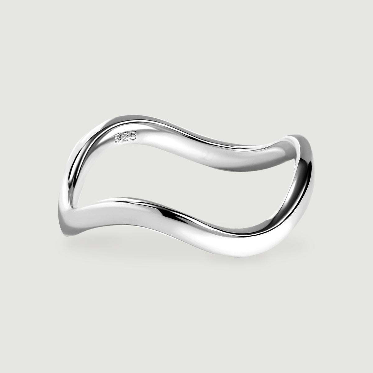 A polished silver ring with a curved band rests on a light gray surface.