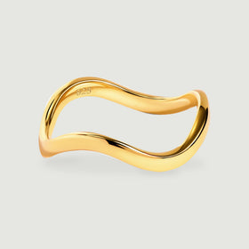 A yellow gold ring with a smooth contoured band is centered above a soft shadow.