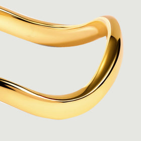 The rounded right side of a yellow gold band catches light against a clean gray background.