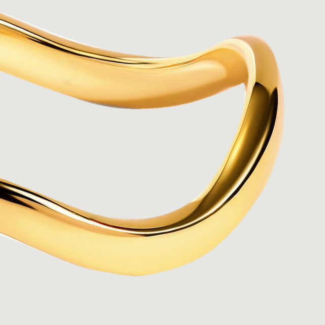 The rounded right side of a yellow gold band catches light against a clean gray background.