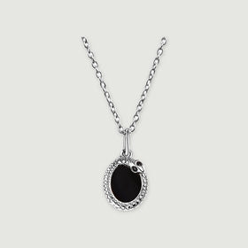 A silver-tone necklace displays a black oval pendant with a textured rim against a pale gray surface.