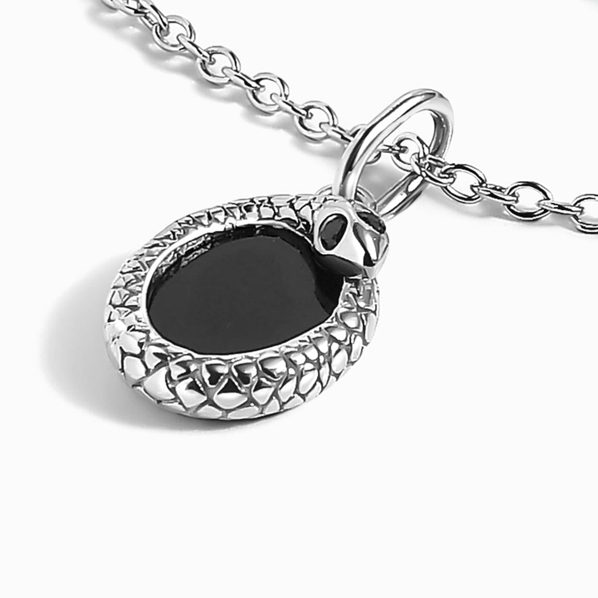 The silver-tone pendant rests at an angle with its black center and sculpted side visible.
