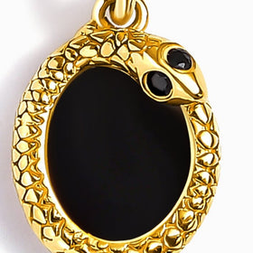 A close view shows the glossy black stone, two small dark accents, and textured yellow gold setting.