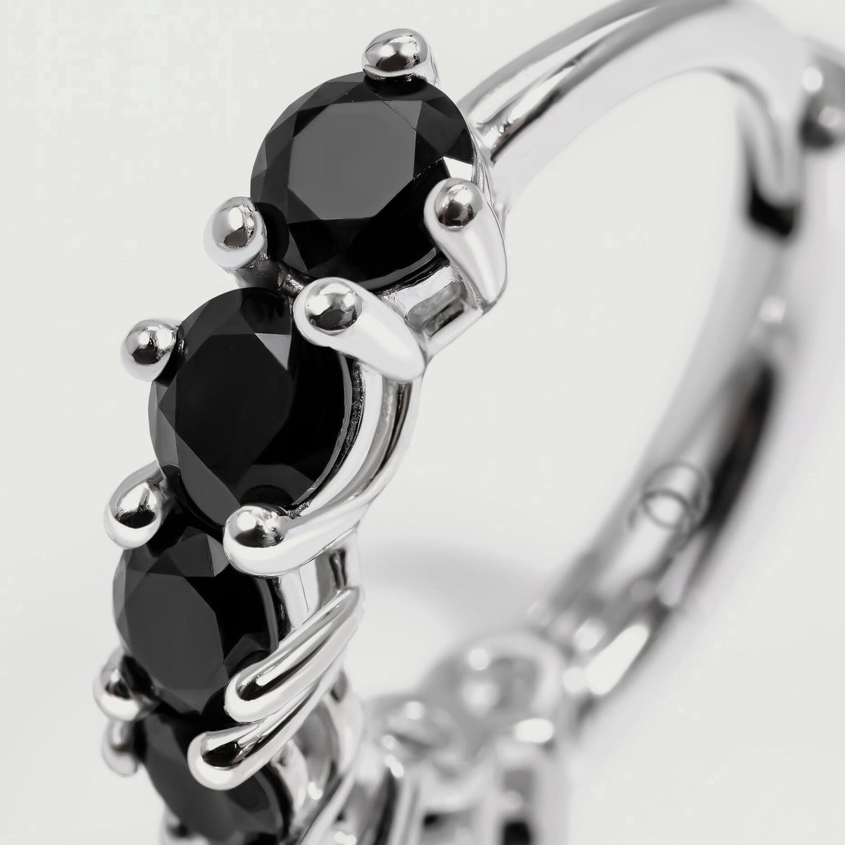 A close-up shows faceted black stones held by rounded silver-colored prongs.