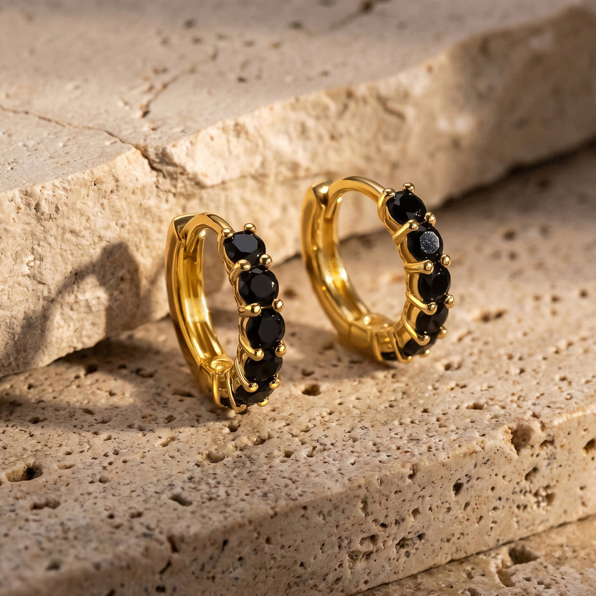 Two gold-colored hoops stand side by side beside a pale stone ledge.