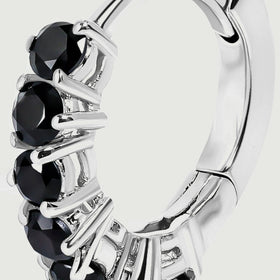An angled silver-colored hoop reveals its curved band, hinge, and black gemstone settings.