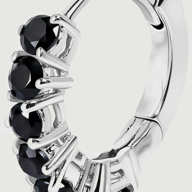 An angled silver-colored hoop reveals its curved band, hinge, and black gemstone settings.