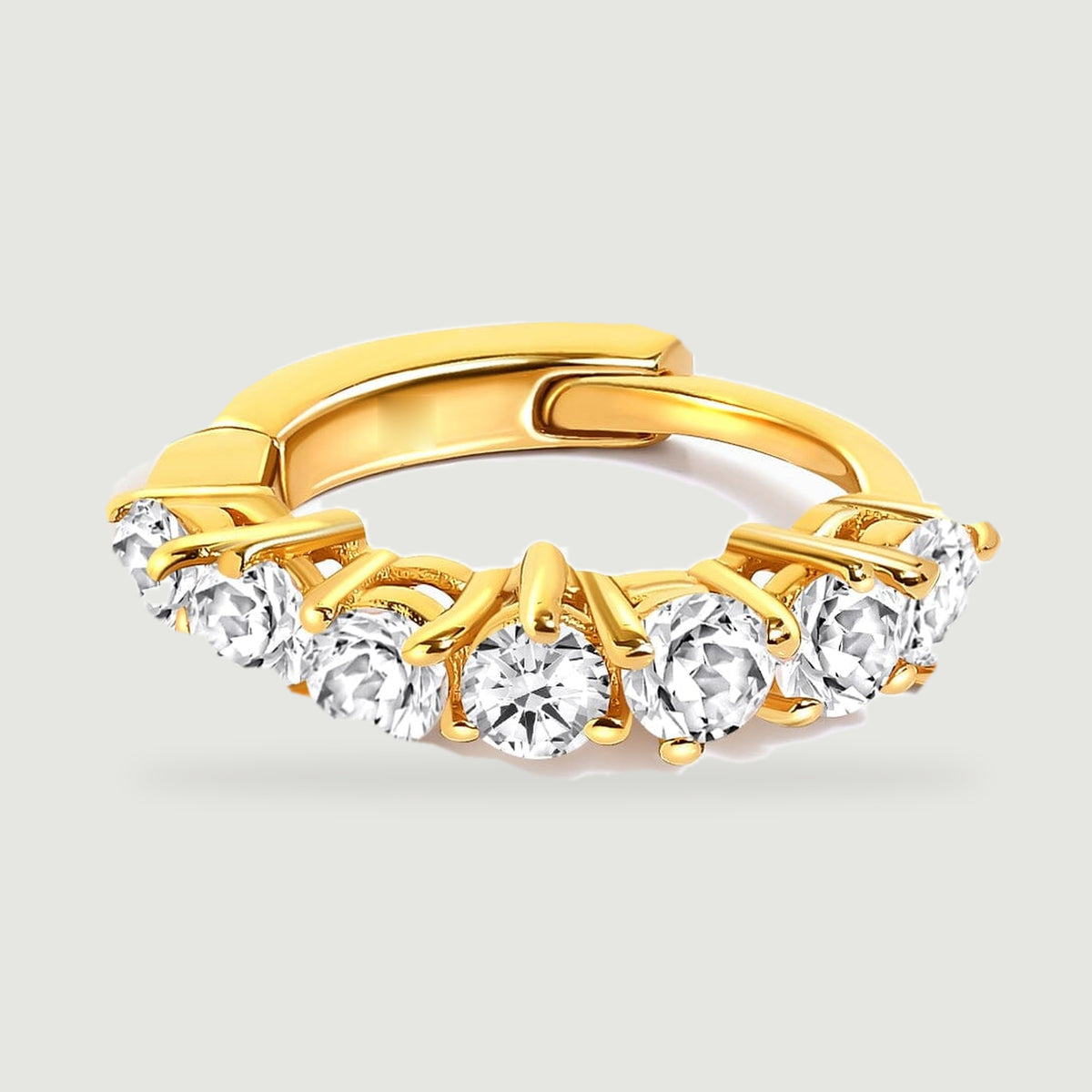 A yellow gold-tone hoop lies flat with its row of white topaz stones facing forward.