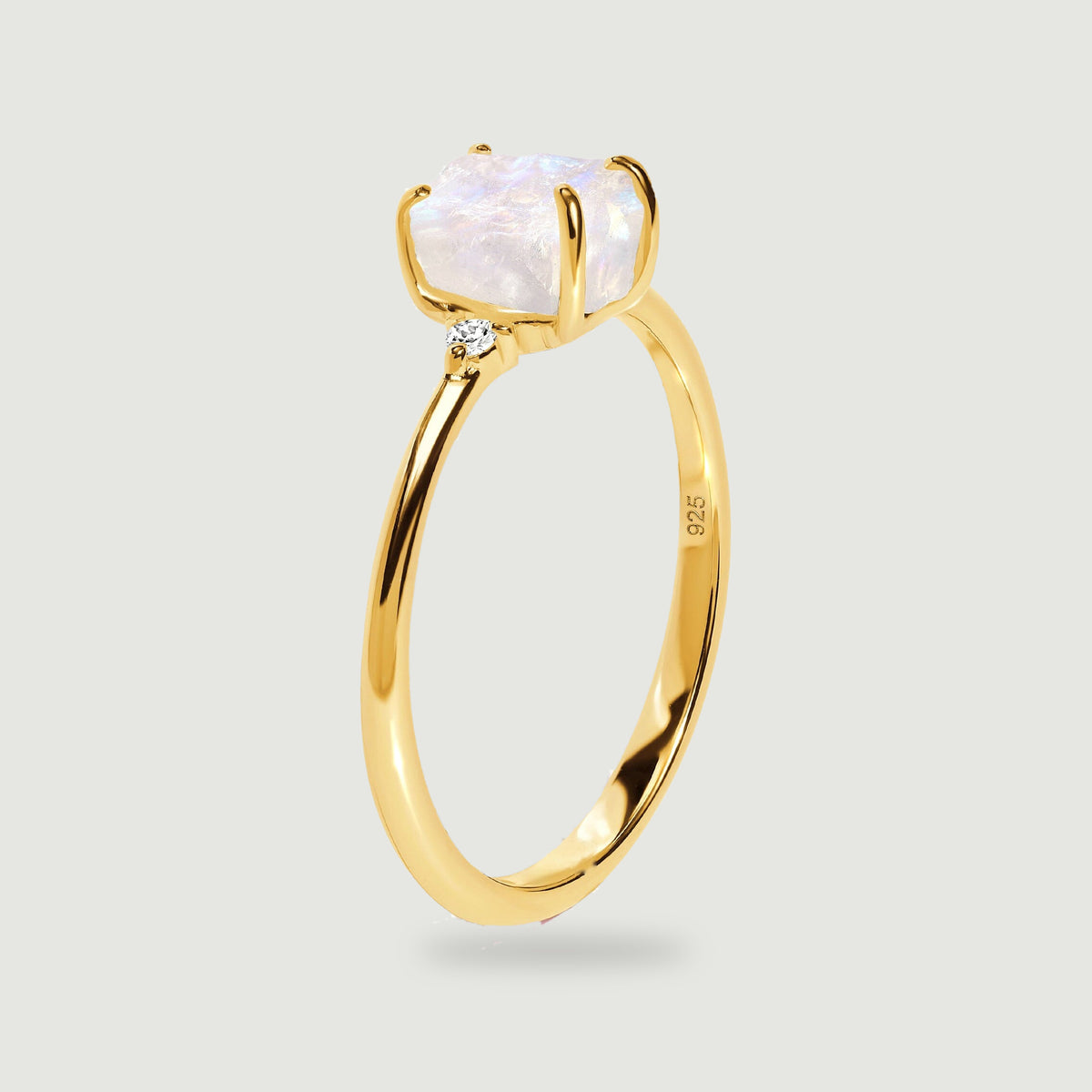 The yellow gold ring is shown from the side with its tall prongs and narrow curved band visible.