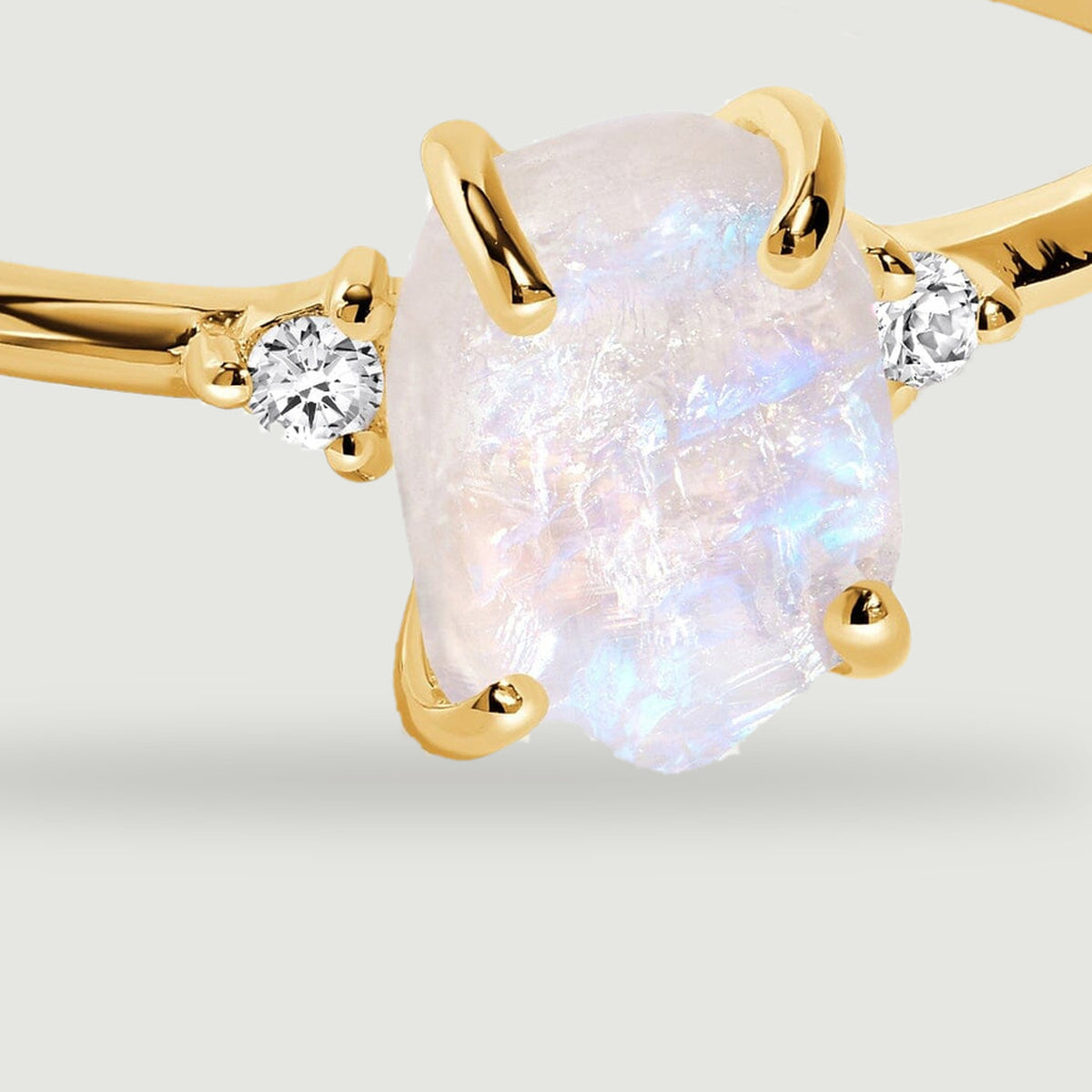 The textured pale center stone is held by polished yellow gold prongs with small round stones on both sides.